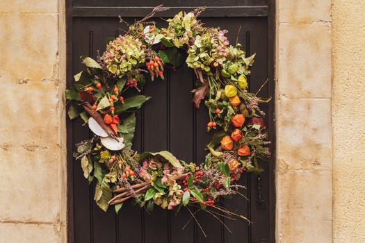 Wreath with the red berries and the dry leaves hanging on a door.