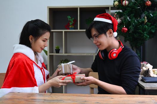 Young couple exchanging Christmas presents while celebrating Christmas together.