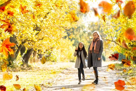 Happy family on autumn walk Mother and daughter walking in the Park and enjoying the beautiful autumn nature. High quality photo