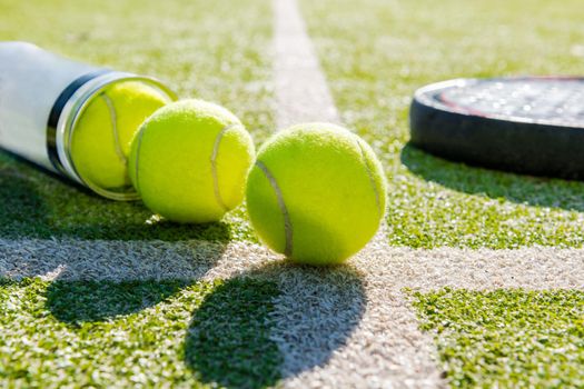 paddle tennis racket and tube with balls on court of artificial turf, indoor sports concept and sporty lifestyle