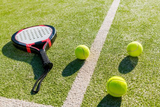 paddle tennis racket and balls on court of artificial grass, indoor sports concept and sporty lifestyle