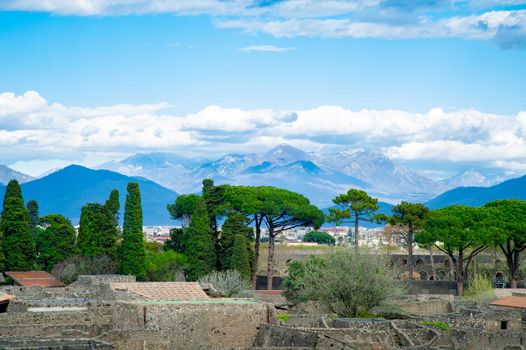 Very beautiful landscape of Pompeii in Italy with trees in the foreground and high mountains and blue sky in the background