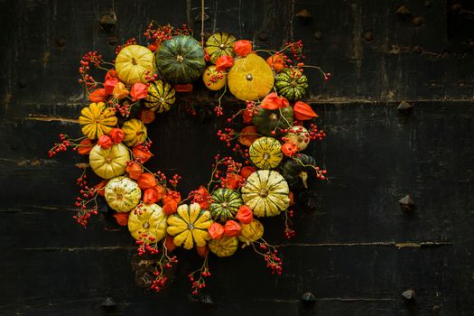Handmade wreath of the small pumpkins and zucchinis on a vintage door Halloween pumpkins