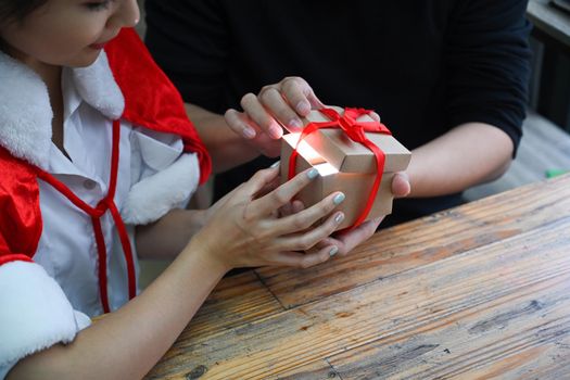 Cropped shot young couple opening Christmas gift box together.