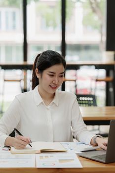 Asian Business Woman or Accountant do math and analyze with calculator and paperwork on desk, account, audit and saving concept.