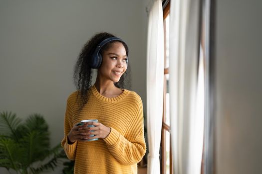 Young woman enjoying music at home. Beautiful young woman listening to the music, drinking coffee and enjoying leisure time at home.