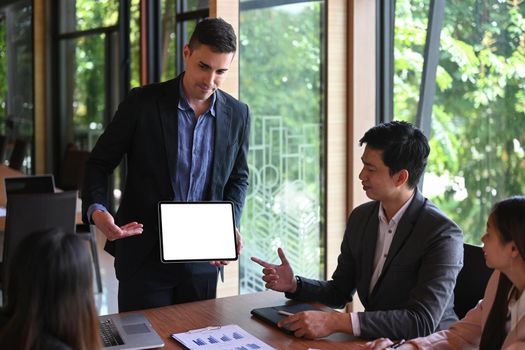 Confident businessman holding digital tablet and presentation of business plan in modern office.