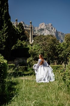 a beautiful woman with long brown hair stay along a path along beautiful bushes in the park