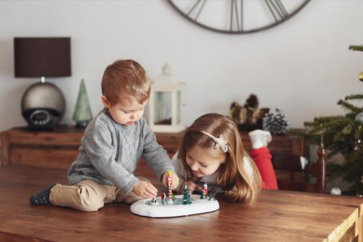 Sister and brother play with ceramic figures for Christmas