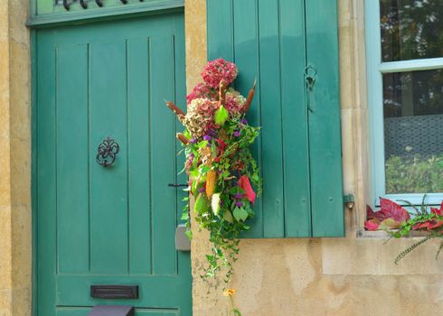 A composition of dried flowers hydrangeas, ivy, cane corn and berries hanging on a vintage door