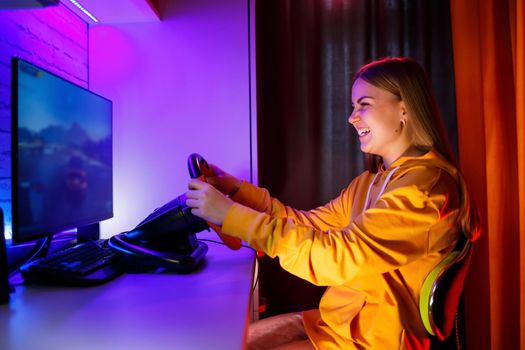girl gamer playing racing on a computer. She uses a steering wheel. emotional play