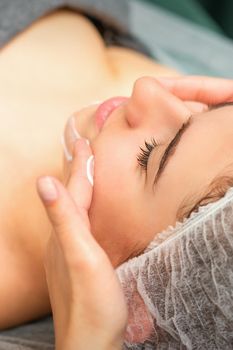 Spa facial skincare. Close-up of a young caucasian woman getting spa moisturizing face massage treatment at beauty spa salon