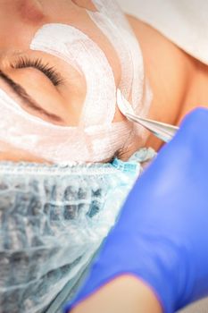 Face peeling at the beautician. Facial treatment. The beautician applies a cleansing face mask to the female patient