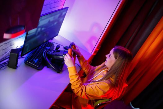 girl gamer playing racing on a computer. She uses a steering wheel. emotional play