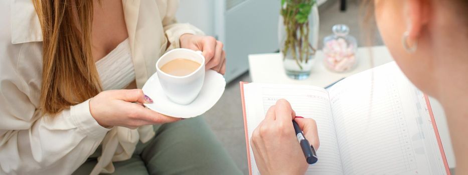 The young caucasian woman has a coffee and appointment with a female doctor in hospital office