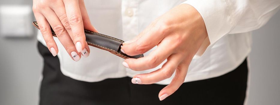 Manicured hands and tools for a manicure. Hands of manicurist take off instrument for a manicure from the leather case in a nail salon