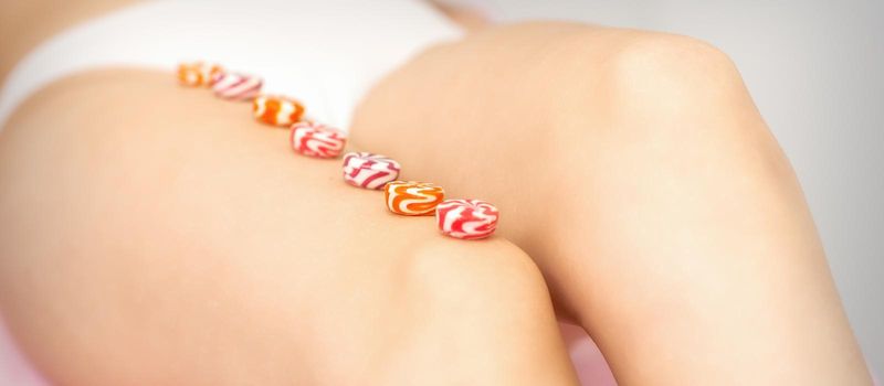 Round candies lying in a row on the female leg with copy space, depilation concept