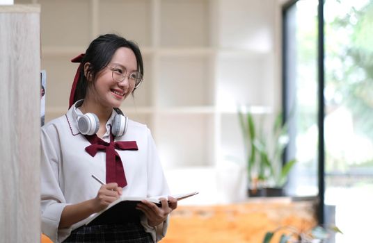 Young asian business woman is standing at a desk and taking notes in a notebook. The concept of education and technology..