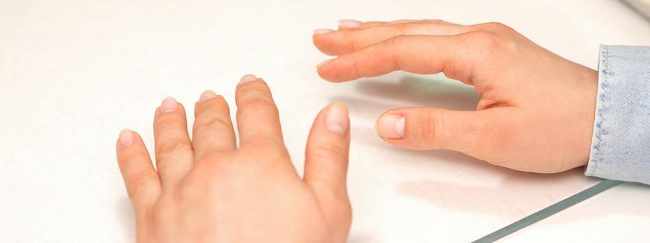 Hands of a young woman with well-groomed nails on the manicure table