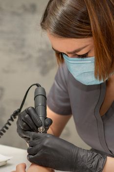 Manicurist removes nail polish uses the electric machine of the nail file during manicure in a nail salon