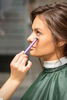 Makeup and hairstyle process. Makeup artist and hairdresser preparing young caucasian woman, working in tandem