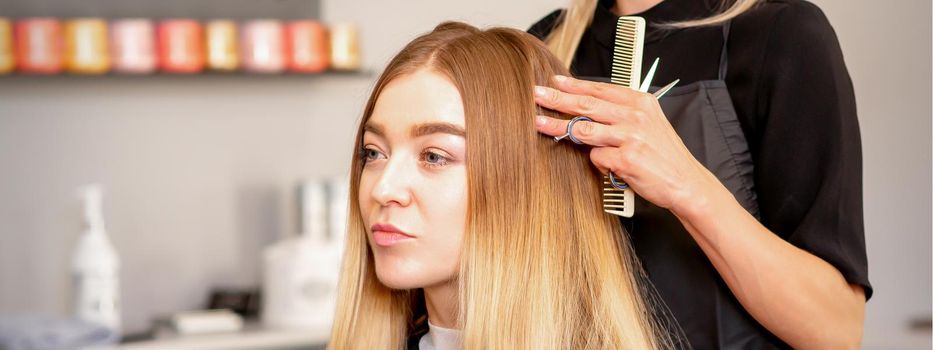 Gorgeous blonde long hair woman and her hairdresser looking and checking out hairstyle. Beautiful hairstyle of a young blonde woman after dying hair in a beauty salon, results of hair treatment