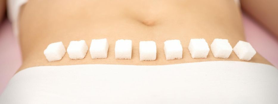 Sugar cubes lying in a row on female bikini zone, the concept of intimate depilation, problems of intimate hygiene