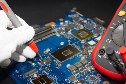 Computer repair service. Engineer repairing laptop mainboard. Hardware developer measure electronic components.