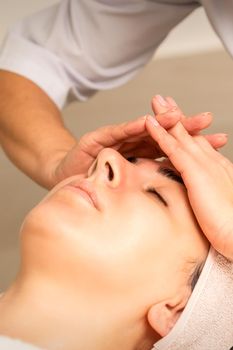 Beautiful young caucasian woman receiving a head massage in a beauty clinic, close up