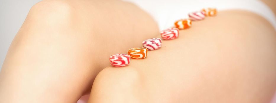 Round candies lying in a row on the female leg with copy space, depilation concept