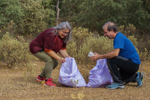 couple of environmentalists collecting garbage from the field in garbage bags. concept of environmental care