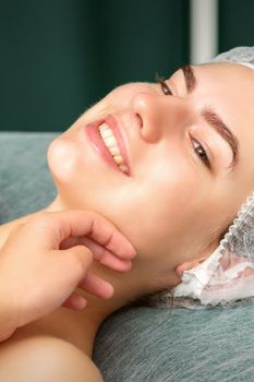 Plastic surgery and beauty concept. Hand of beautician examining and touching the face of beautiful young smiling caucasian woman