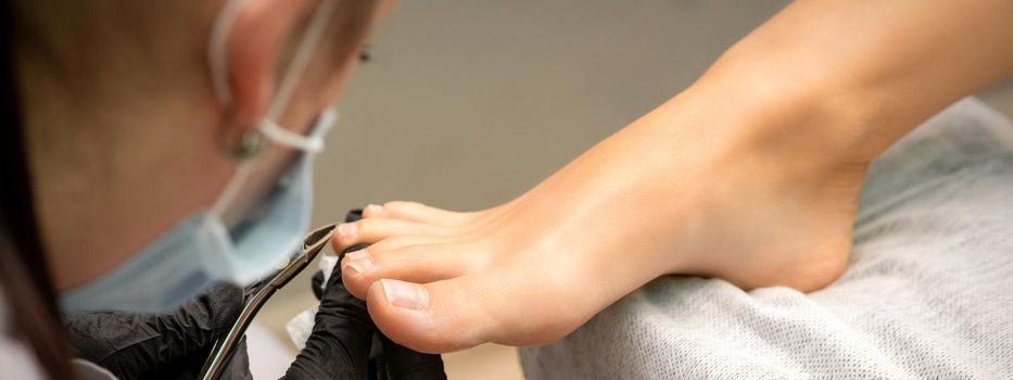 Pedicure master using nail nippers while trimming toenails in a pedicure salon