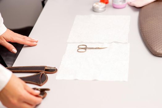 Hands of manicure master prepare nail care tools on a white table