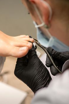 Pedicure master using nail nippers while trimming toenails in a pedicure salon