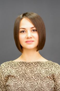 Beautiful young caucasian brunette woman with short hairstyle smiling and looking at camera against dark gray background with copy space