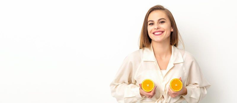 Young Caucasian smiling woman holding slices orange over isolated white background, breast health concept