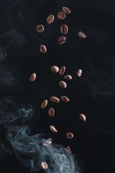 Fresh ccoffee beans in flight on a dark background whith smoke