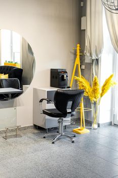 Modern small bright hair and beauty salon in black and yellow colors with gray walls and floor