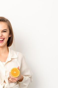 Young Caucasian smiling woman holding slices orange over isolated white background, breast health concept