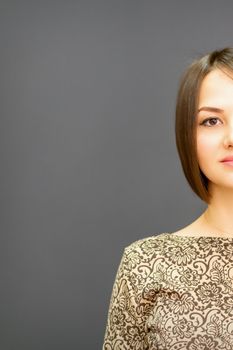 Beautiful young caucasian brunette woman with short hairstyle smiling and looking at camera against dark gray background with copy space