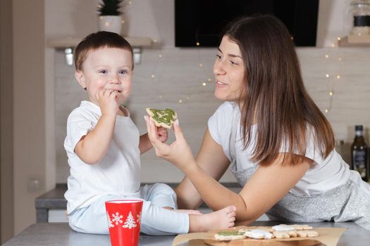 Mom and child are in the kitchen trying cooked Christmas cookies. A series of photos from everyday life in a real interior