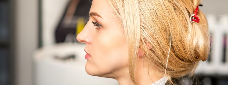 Gorgeous profile of caucasian beauty blonde woman with beautiful hairstyle over hair salon background