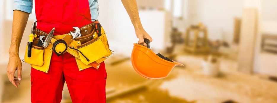 Worker with a diy tool belt over construction background