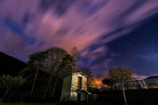 wonderful starry night sky with the clouds over a farmhouse small shed at the countryside, observation of the universe concept