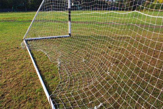 Old football goal against the background of the football field and autumn forest