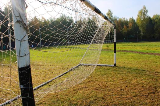 Old football goal against the background of the football field and autumn forest