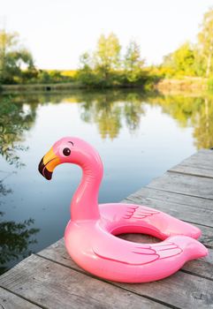 Inflatable pool toy, pink flamingo. Outdoor recreation outside the city, flamingos on a wooden pier