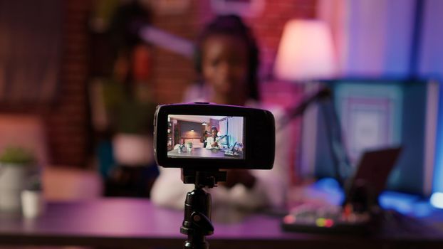 Selective focus on digital video camera screen recording african american woman streaming live internet show from home. Content creator filming entertainment show for vlog social media post.