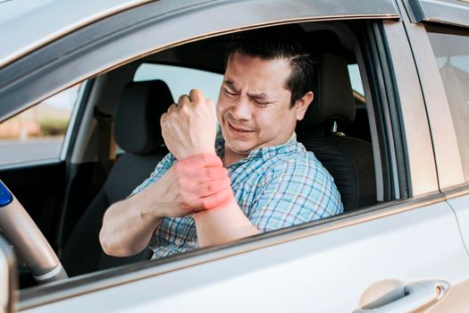 Driver suffering from wrist pain. Sore driver man touching his wrist. Driver with hand pain. Suffering driver at the wheel rubbing his arm from so much driving .Sore man tired of driving